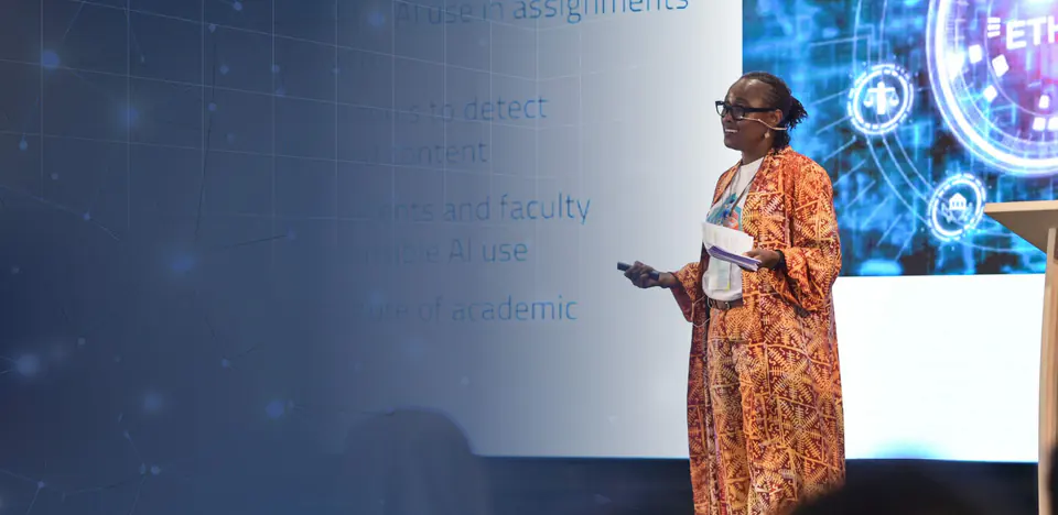 Dr. Égo Obi presenting on stage, an AI ethics slide on the screen behind her